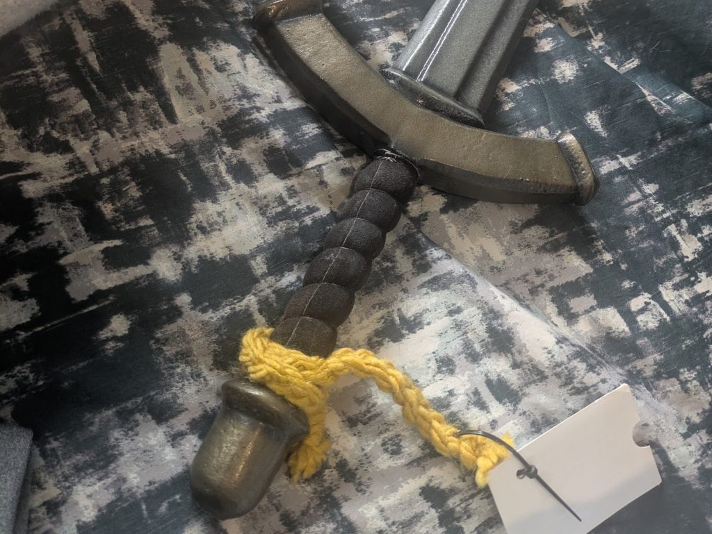 The yellow woolen braid from the previous image is tied around the hilt of a larp sword. 